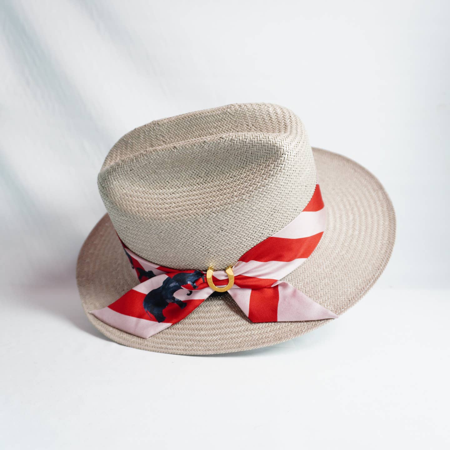 Beige straw hat with a red and white striped ribbon on a light gray background
