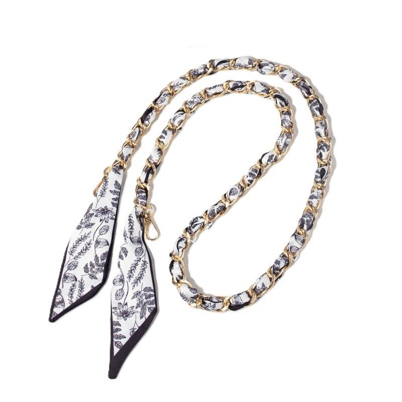 Black and white floral scarf woven through gold chain bag strap with clasps.