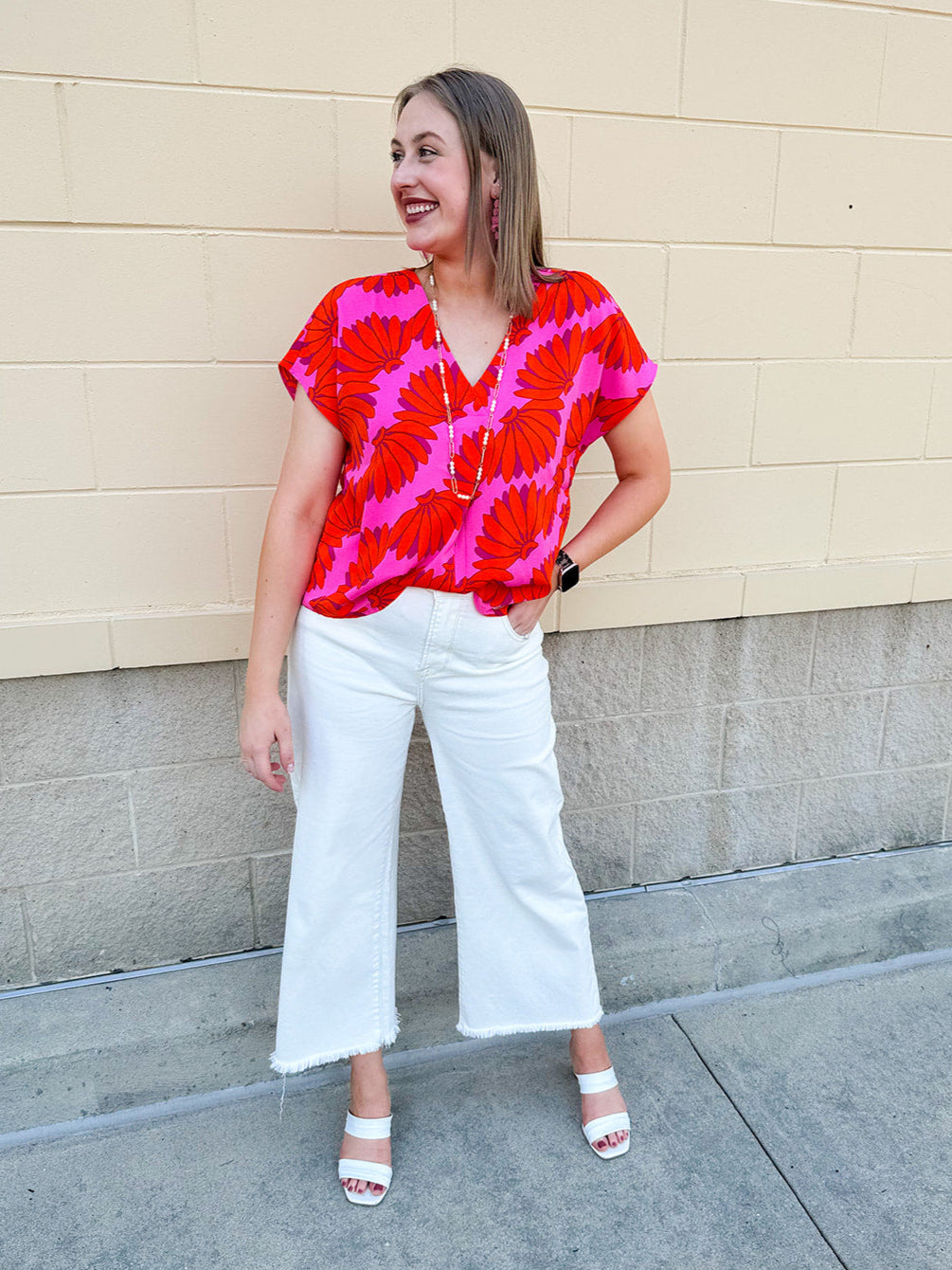 Banana and floral print top in orange and hot pink with V-neck and short dolman sleeves, displayed on hanger against neutral background