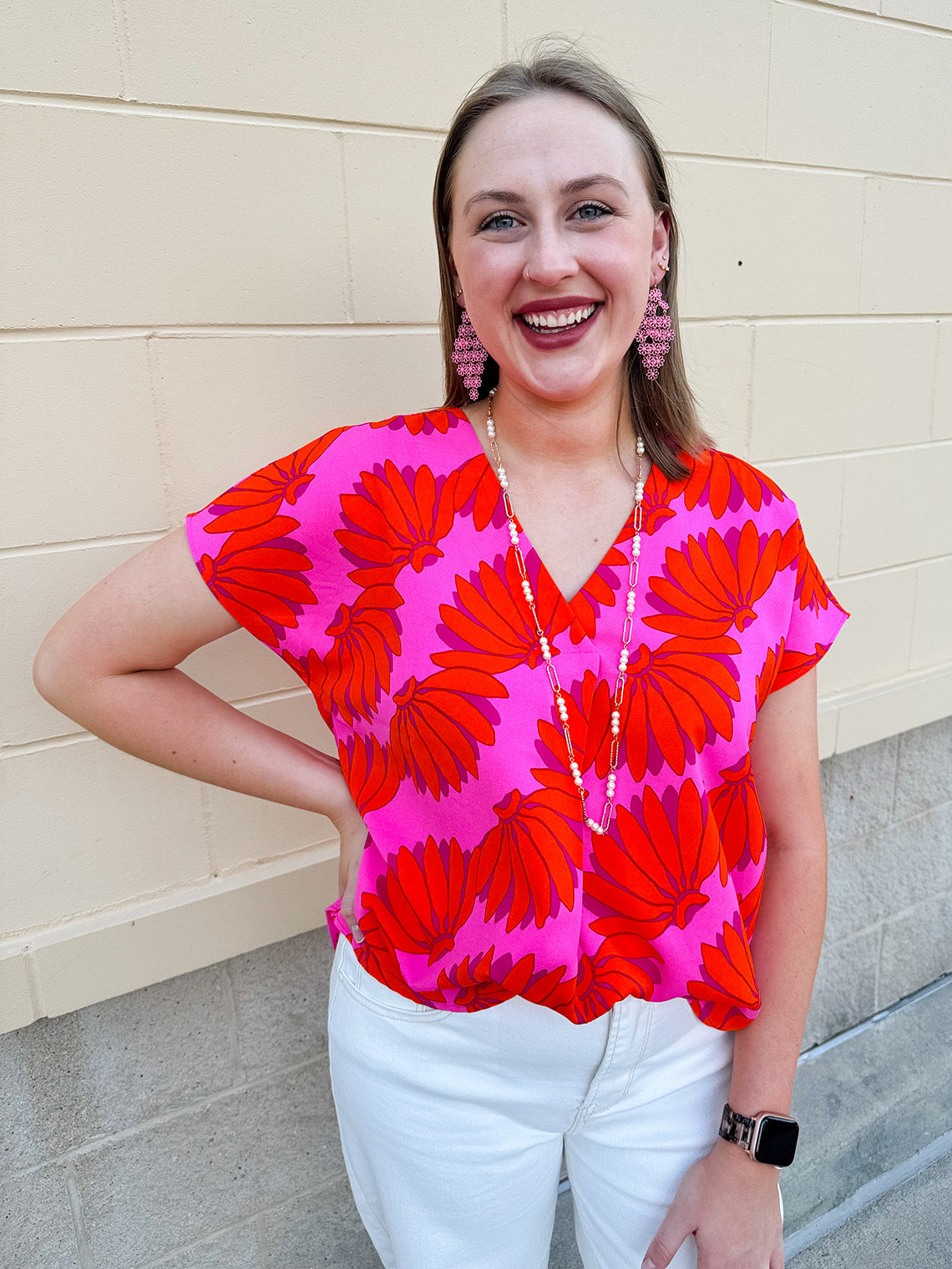 Banana and floral print top in orange and hot pink with V-neck and short dolman sleeves, displayed on hanger against neutral background
