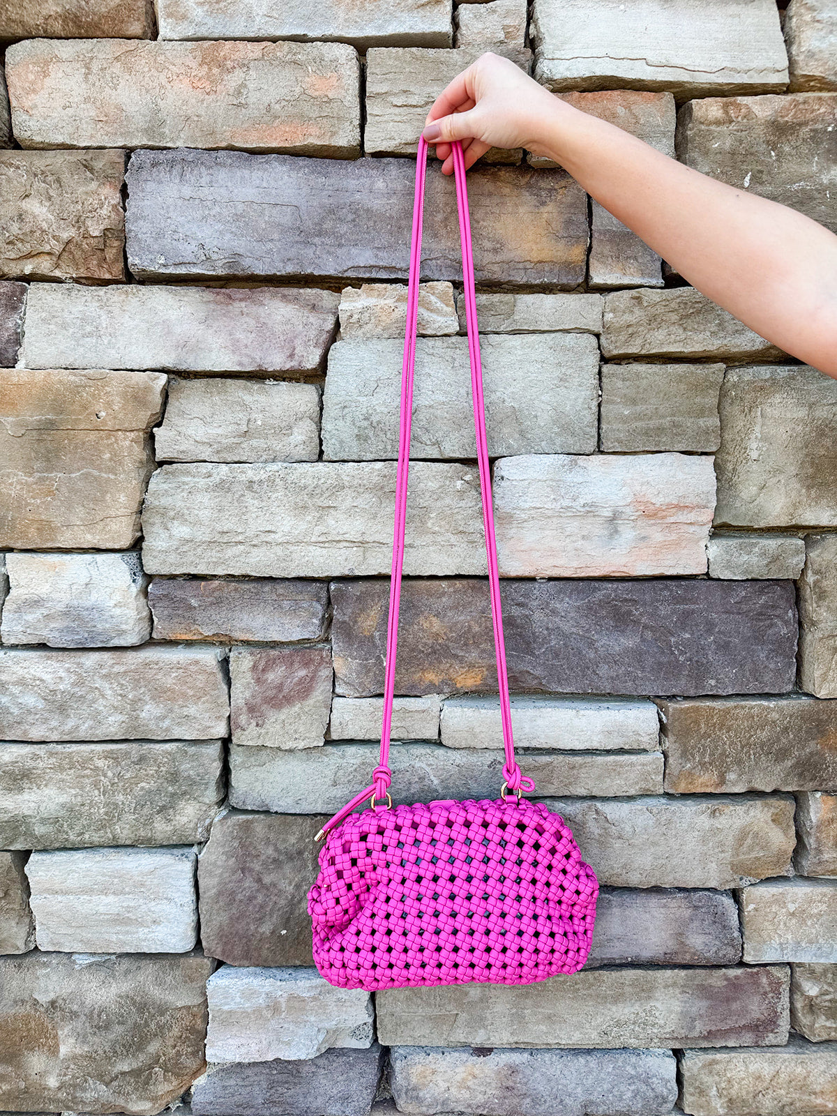 Hot pink woven handbag with a braided texture and knotted strap detail, offering a vibrant and chic everyday style.
