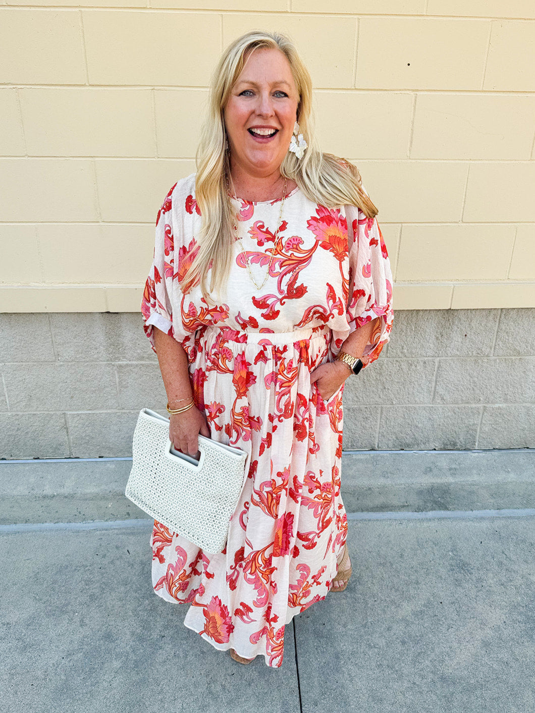 Cream midi dress with pink and orange floral print, scoop neckline, elastic waist, and flowy dolman sleeves.