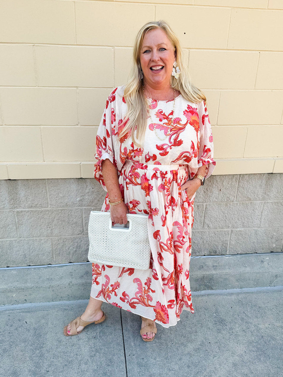 Cream midi dress with pink and orange floral print, scoop neckline, elastic waist, and flowy dolman sleeves.