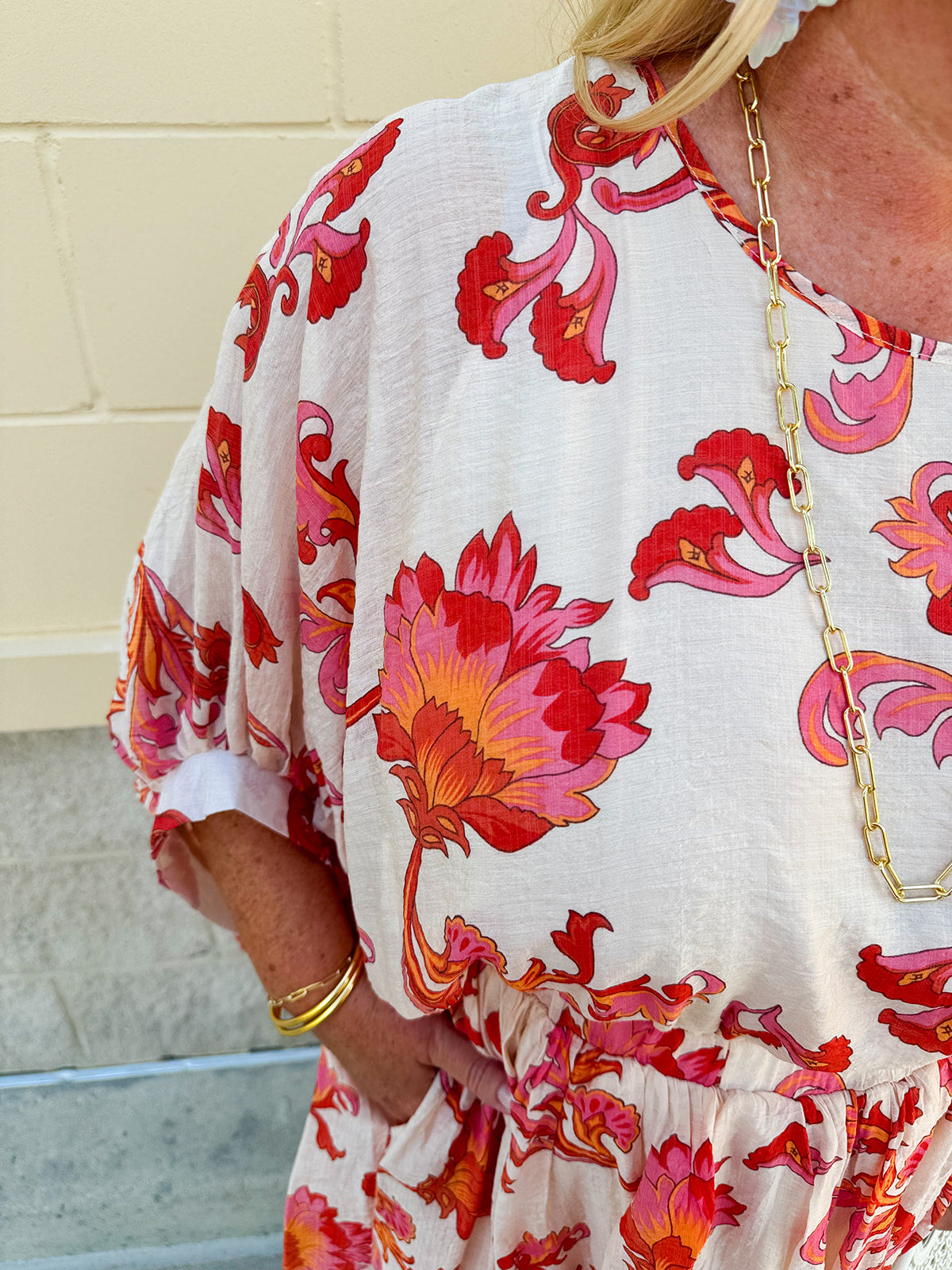 Cream midi dress with pink and orange floral print, scoop neckline, elastic waist, and flowy dolman sleeves.