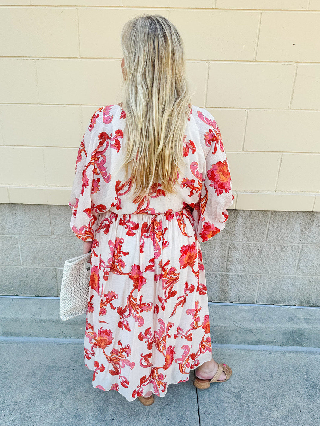 Cream midi dress with pink and orange floral print, scoop neckline, elastic waist, and flowy dolman sleeves.