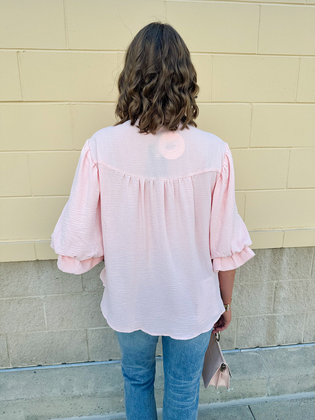 Blush blouse with V-neckline, balloon sleeves, front pleat, and ruffle-trimmed cuffs