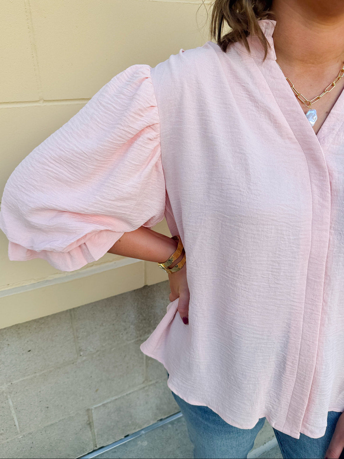 Blush blouse with V-neckline, balloon sleeves, front pleat, and ruffle-trimmed cuffs