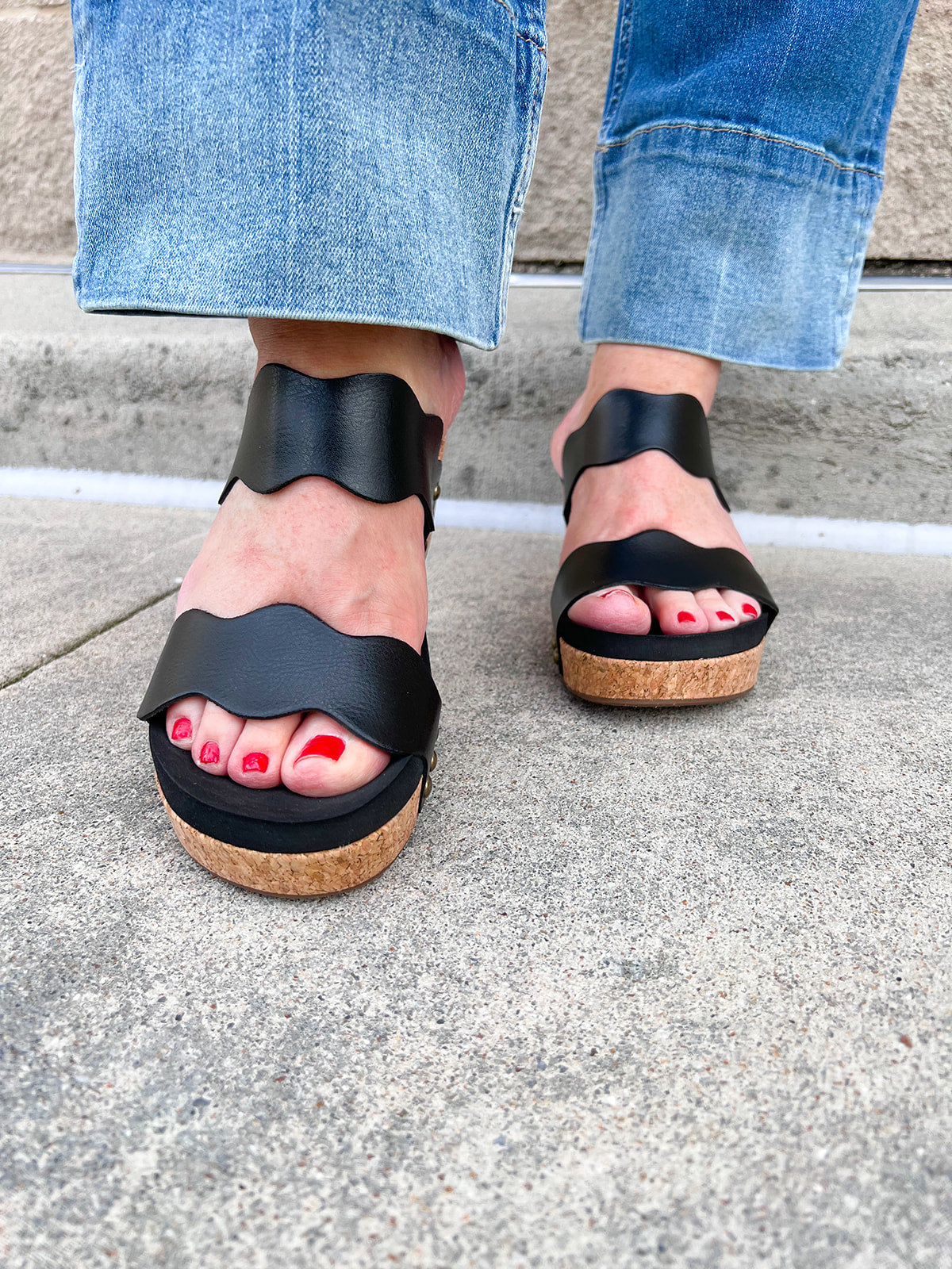 Black scalloped wedge sandals with cork sole, gold hardware accents, and dual straps—stylish and comfortable for everyday wear.