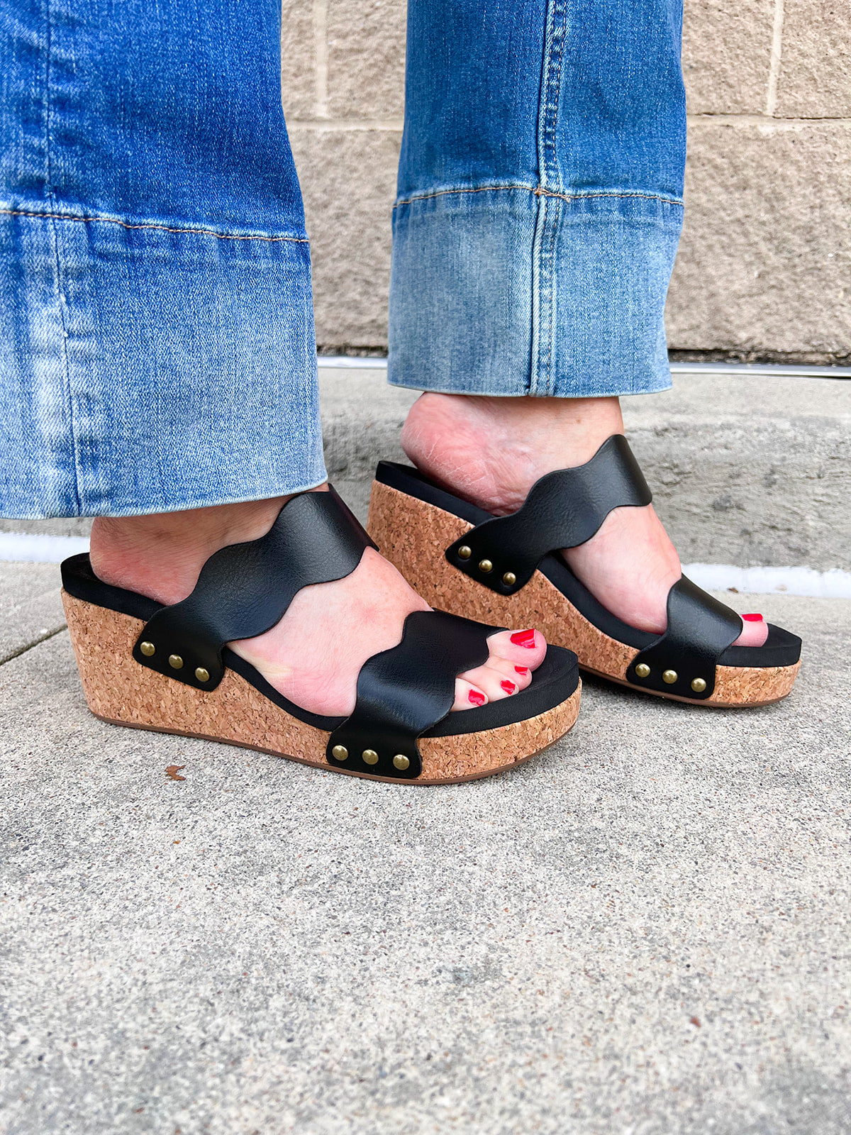 Black scalloped wedge sandals with cork sole, gold hardware accents, and dual straps—stylish and comfortable for everyday wear.