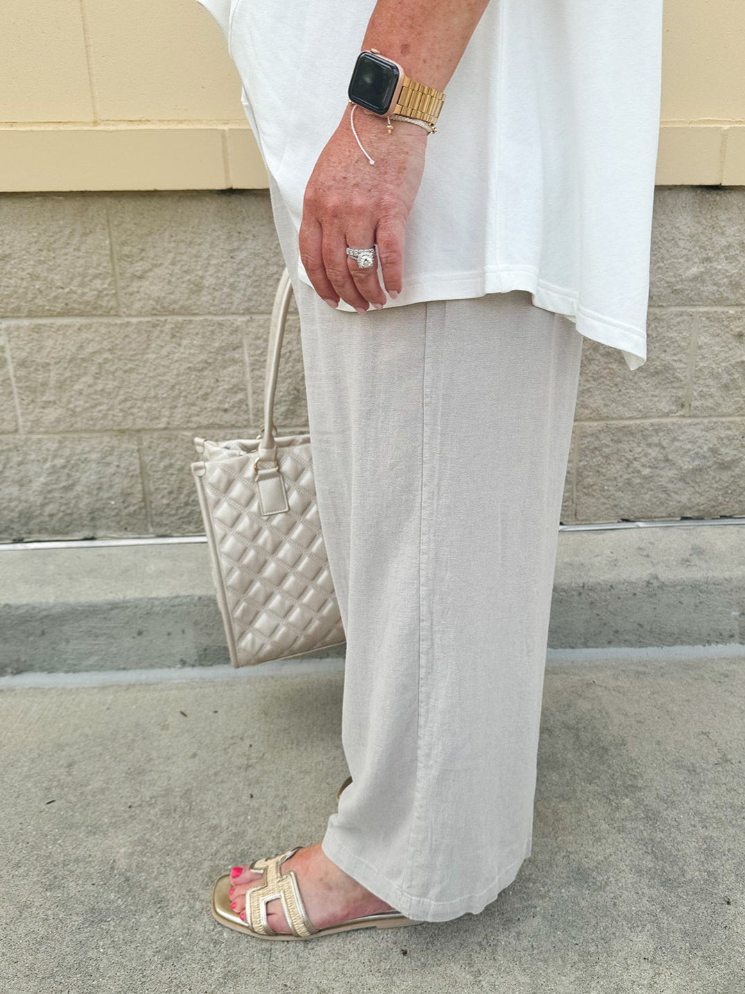Wide-leg linen pants in a stone color with high-rise waist and pockets, styled for casual elegance.