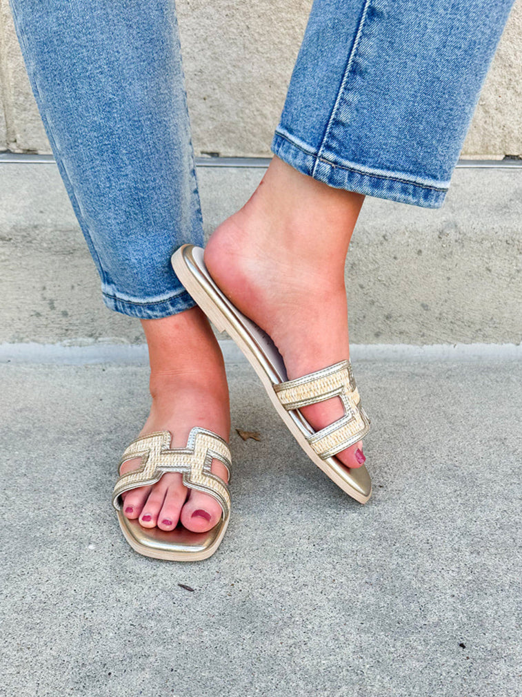 Ena Raffia H-Cutout Slides featuring a breathable raffia strap and modern H-cutout design, styled on a clean surface to showcase their chic, casual summer look and cushioned footbed
