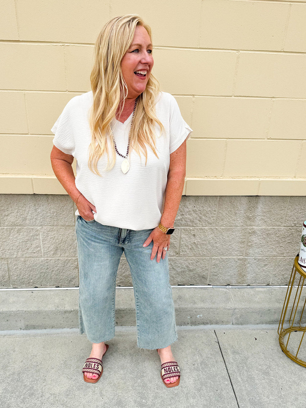 Lightweight oatmeal V-neck top with cap sleeves, styled casually for Gameday. The neutral tone and relaxed fit offer a versatile, polished look.