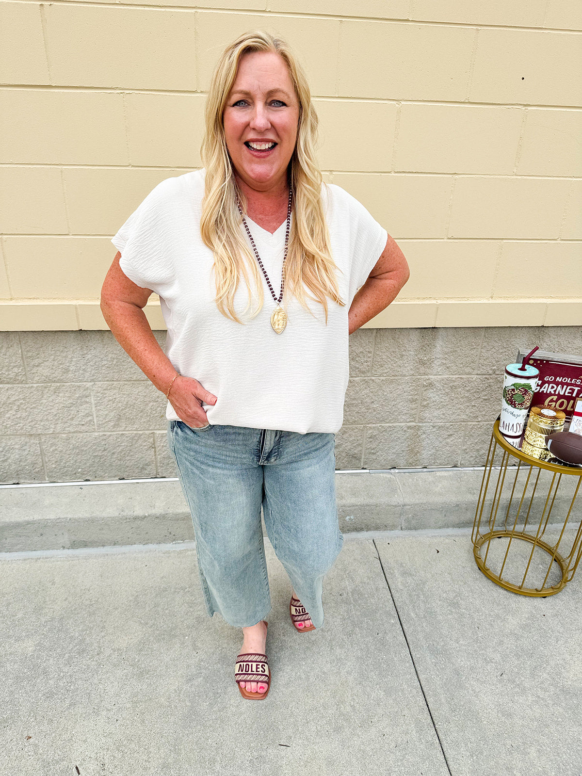 Lightweight oatmeal V-neck top with cap sleeves, styled casually for Gameday. The neutral tone and relaxed fit offer a versatile, polished look.