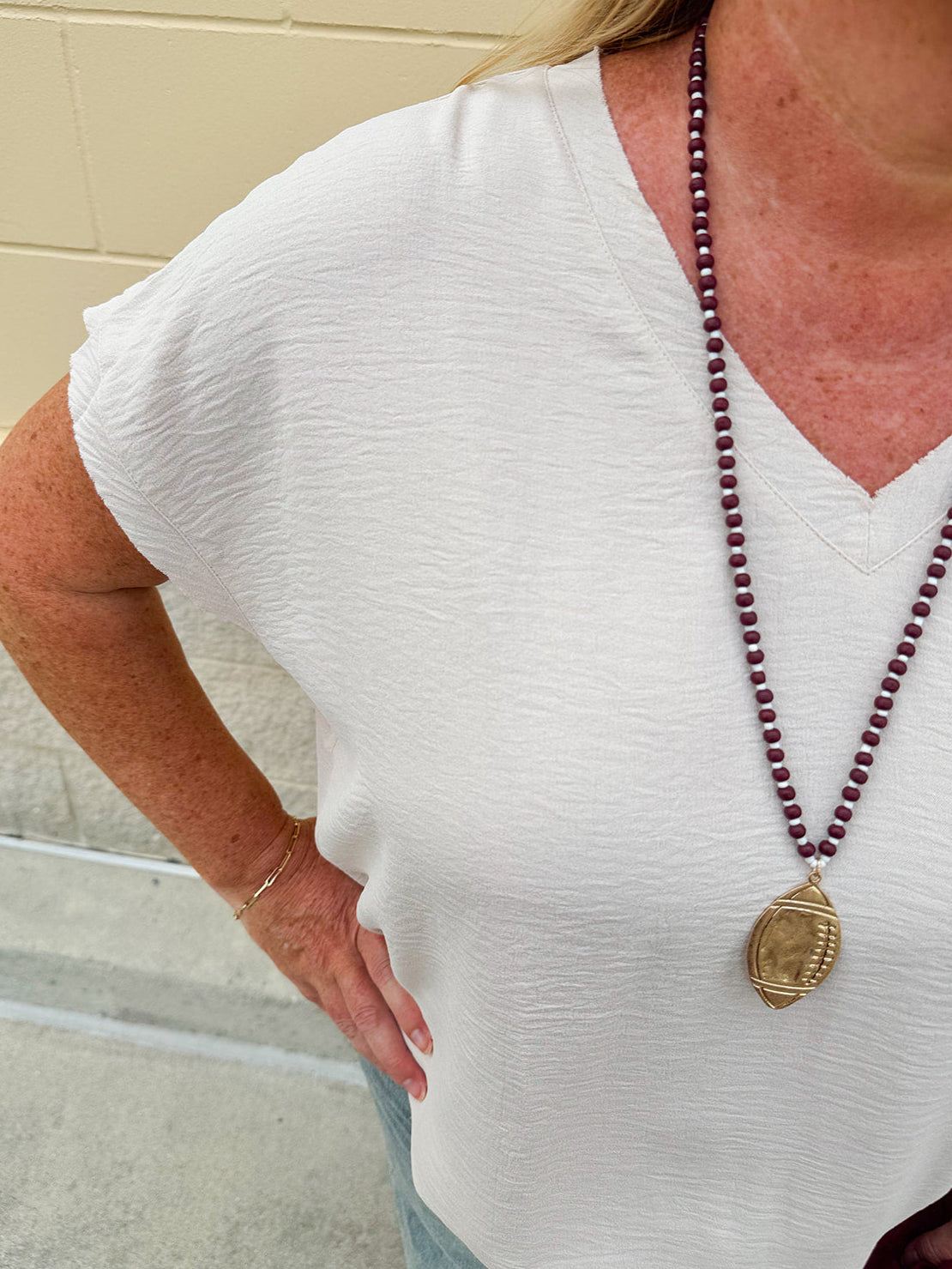 Lightweight oatmeal V-neck top with cap sleeves, styled casually for Gameday. The neutral tone and relaxed fit offer a versatile, polished look.