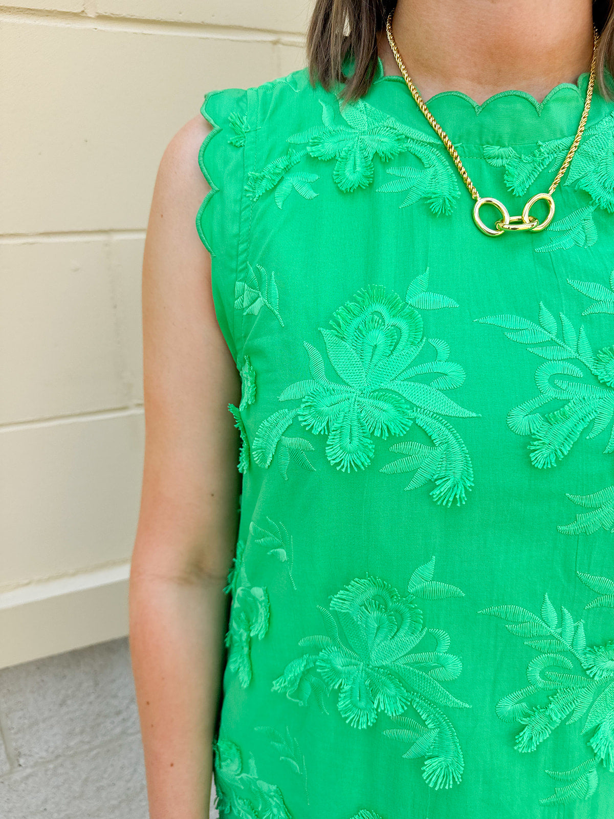 Green sleeveless mini dress with 3D floral appliqués, scalloped hem, and tone-on-tone embroidered details—elegant and lightweight.