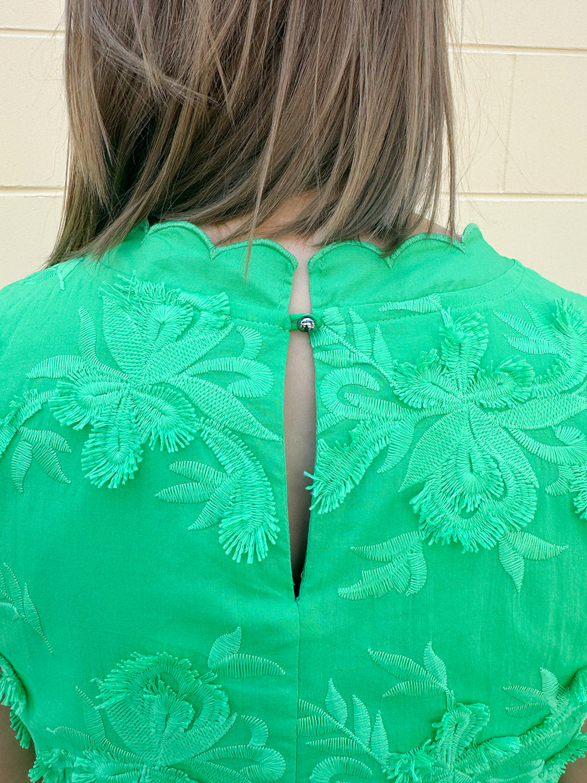 Green sleeveless mini dress with 3D floral appliqués, scalloped hem, and tone-on-tone embroidered details—elegant and lightweight.