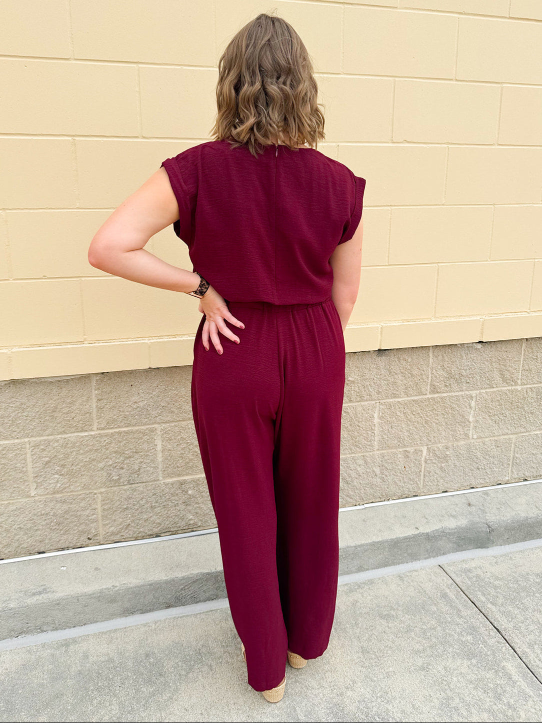 Garnet short-sleeve jumpsuit with elastic waist, front tie, high scoop neckline, and side pockets. Sporty, flattering, and perfect for Gameday style.
