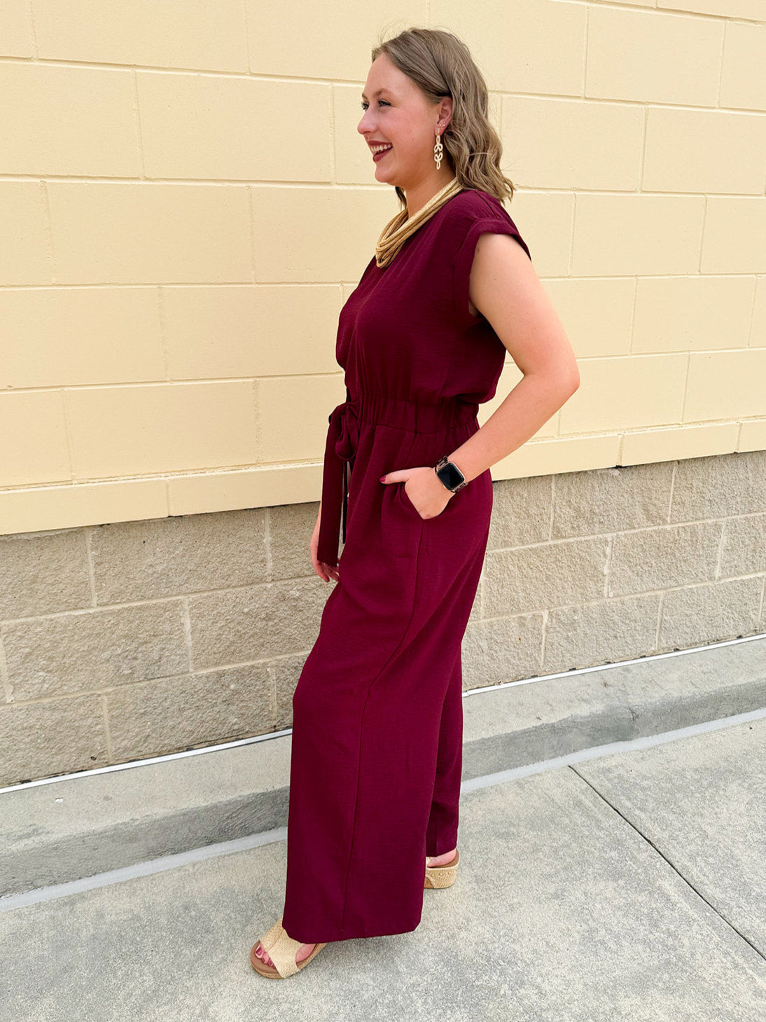 Garnet short-sleeve jumpsuit with elastic waist, front tie, high scoop neckline, and side pockets. Sporty, flattering, and perfect for Gameday style.