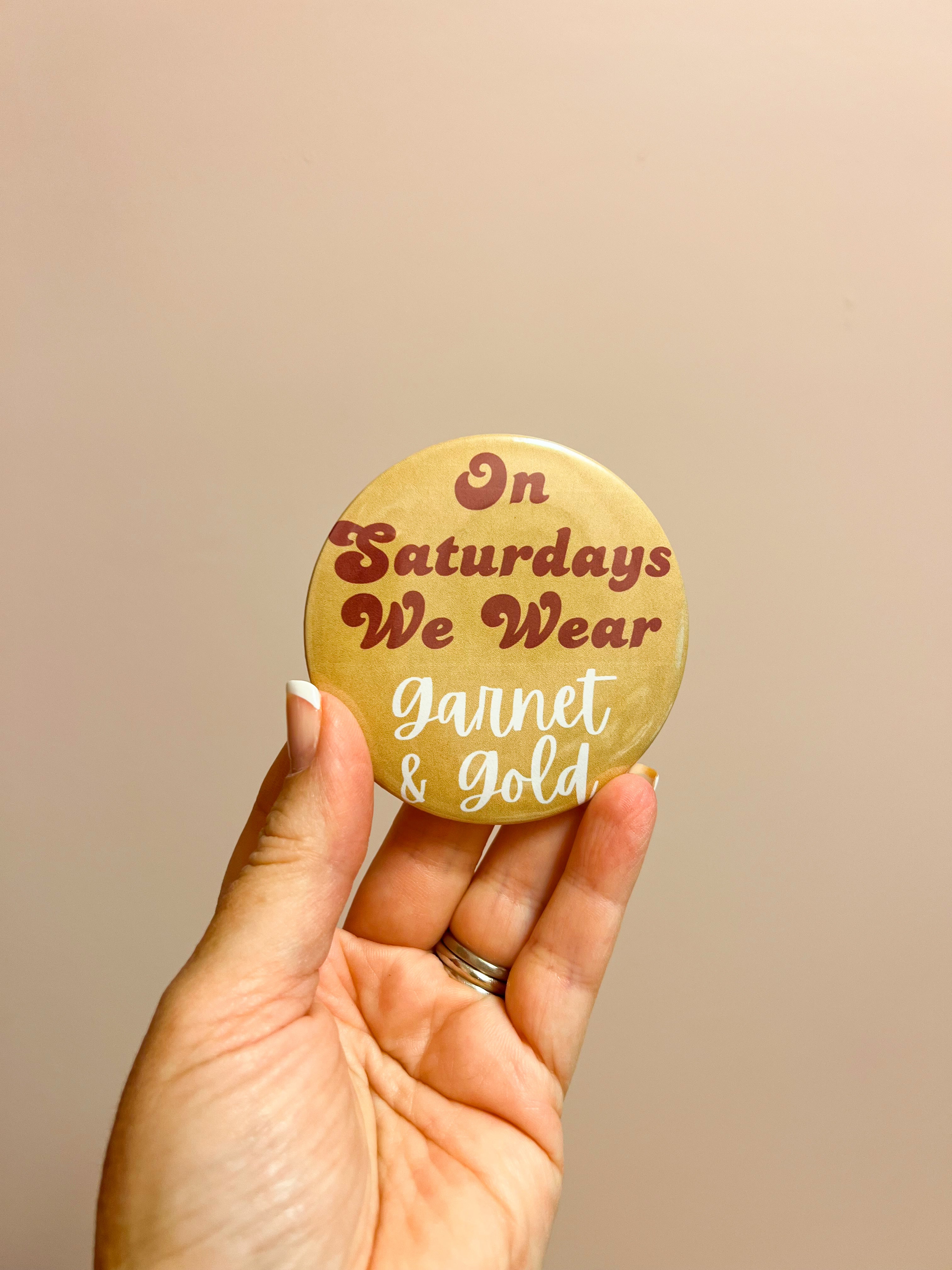Gold button with garnet and white lettering reading “On Saturdays We Wear” styled for FSU game day.