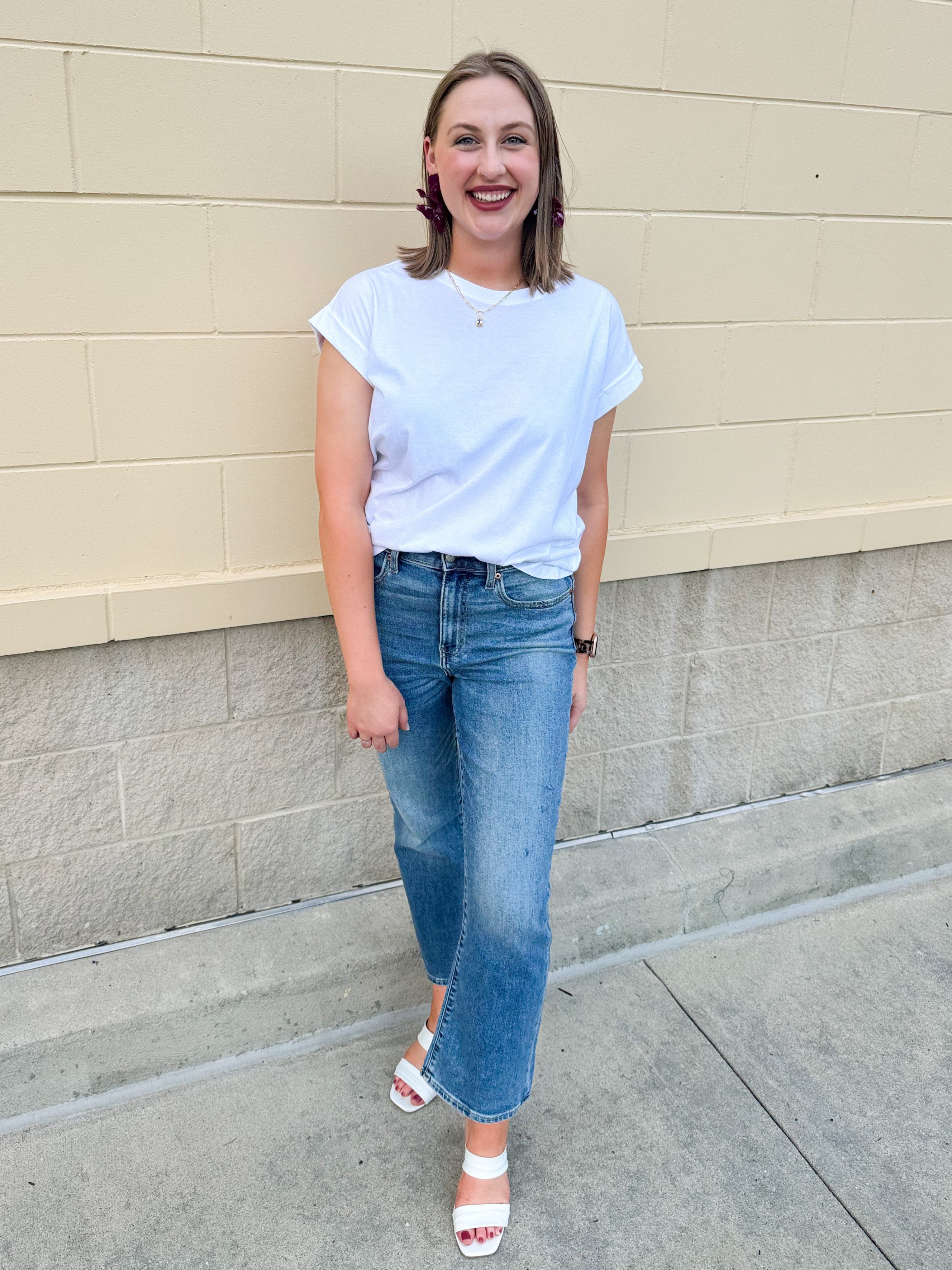 White rolled sleeve tee displayed on hanger or model, showing relaxed fit and classic style.