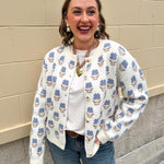 Cream floral jacquard cardigan with blue flowers, button-up front, long sleeves, and crewneck style.