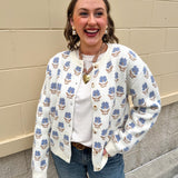 Cream floral jacquard cardigan with blue flowers, button-up front, long sleeves, and crewneck style.