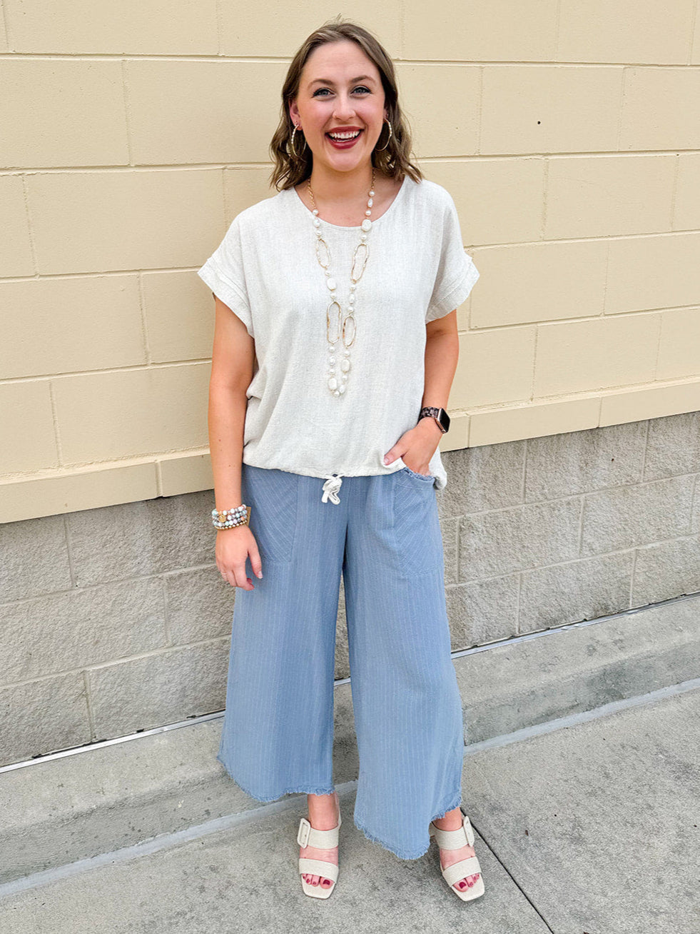 Linen-cotton blend short-sleeve top with front tie and raw hem in a soft neutral oatmeal shade.
