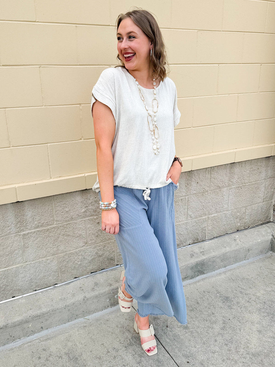 Linen-cotton blend short-sleeve top with front tie and raw hem in a soft neutral oatmeal shade.