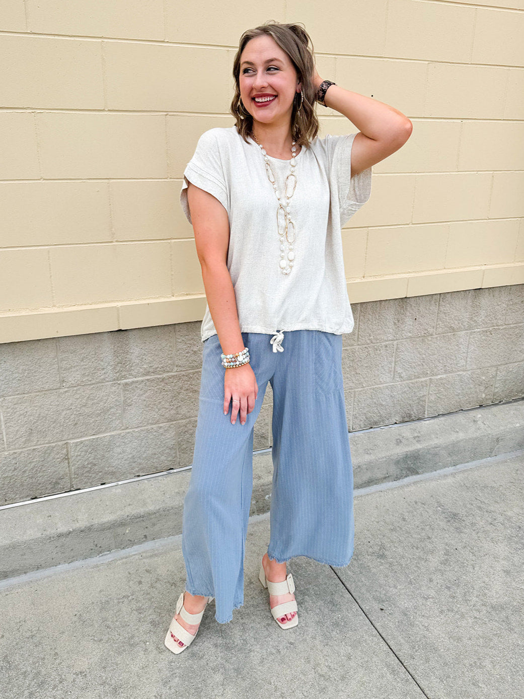 Linen-cotton blend short-sleeve top with front tie and raw hem in a soft neutral oatmeal shade.