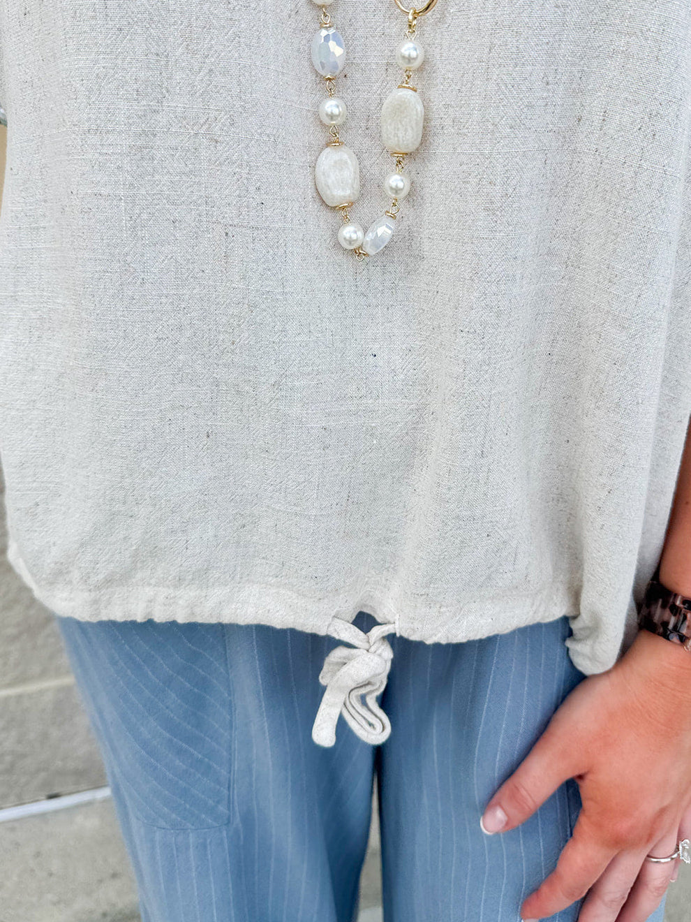 Linen-cotton blend short-sleeve top with front tie and raw hem in a soft neutral oatmeal shade.