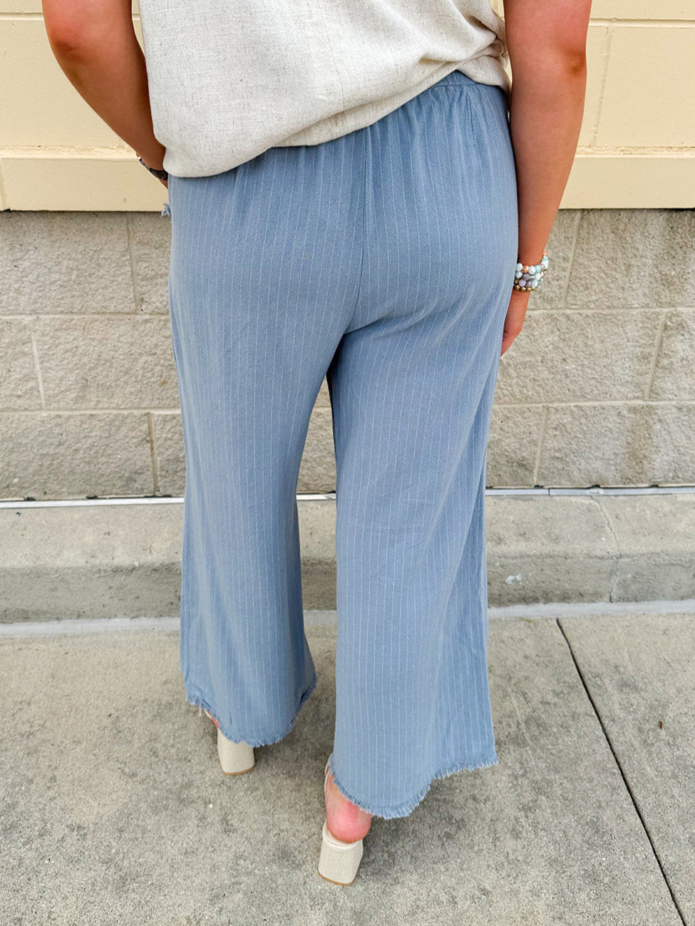 Light blue striped linen blend wide-leg pants with elastic waist, front pockets, and frayed details for an easy, relaxed fit.
