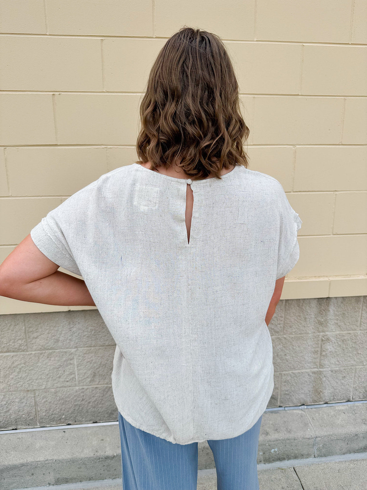 Linen-cotton blend short-sleeve top with front tie and raw hem in a soft neutral oatmeal shade.