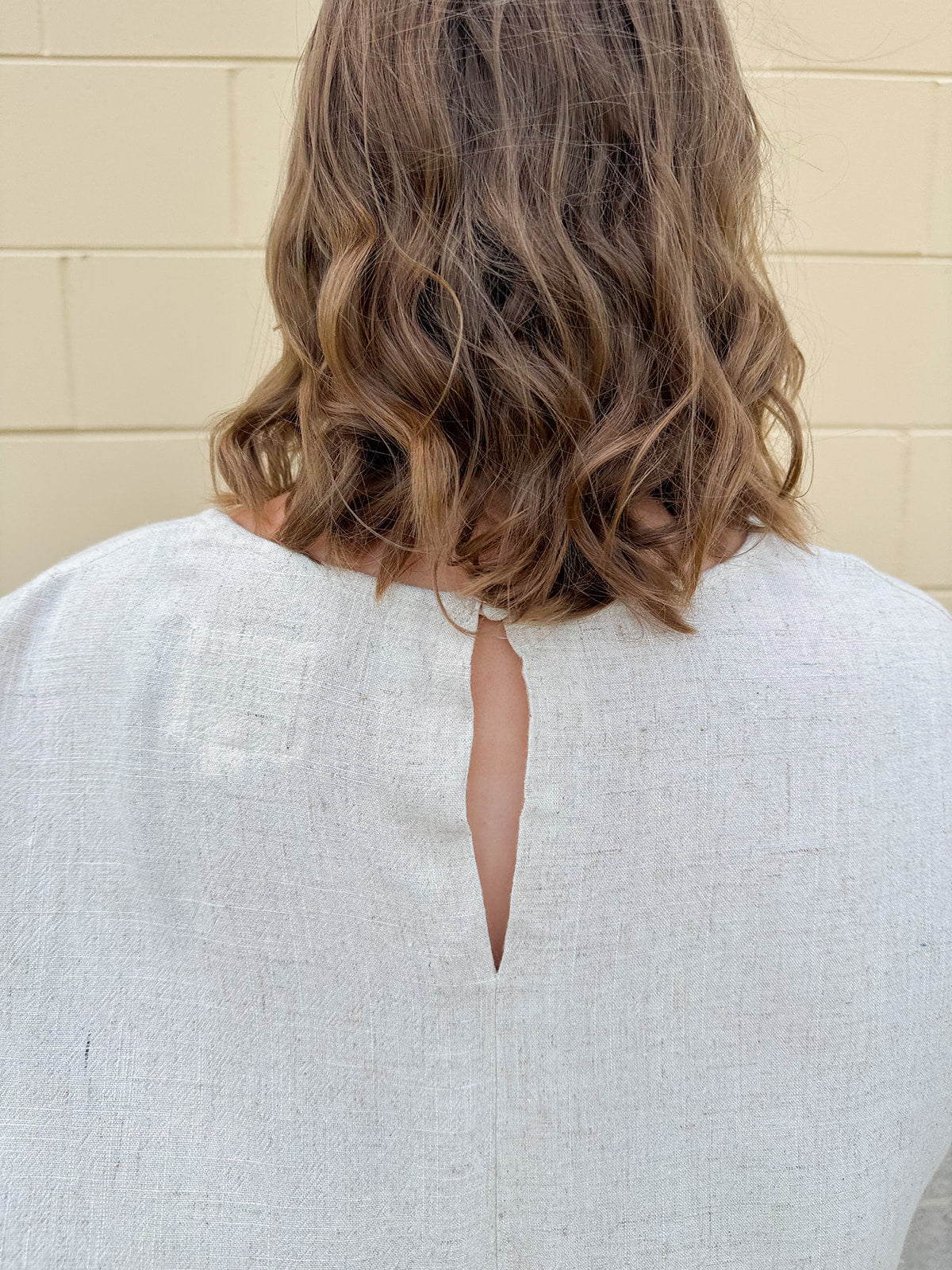 Linen-cotton blend short-sleeve top with front tie and raw hem in a soft neutral oatmeal shade.