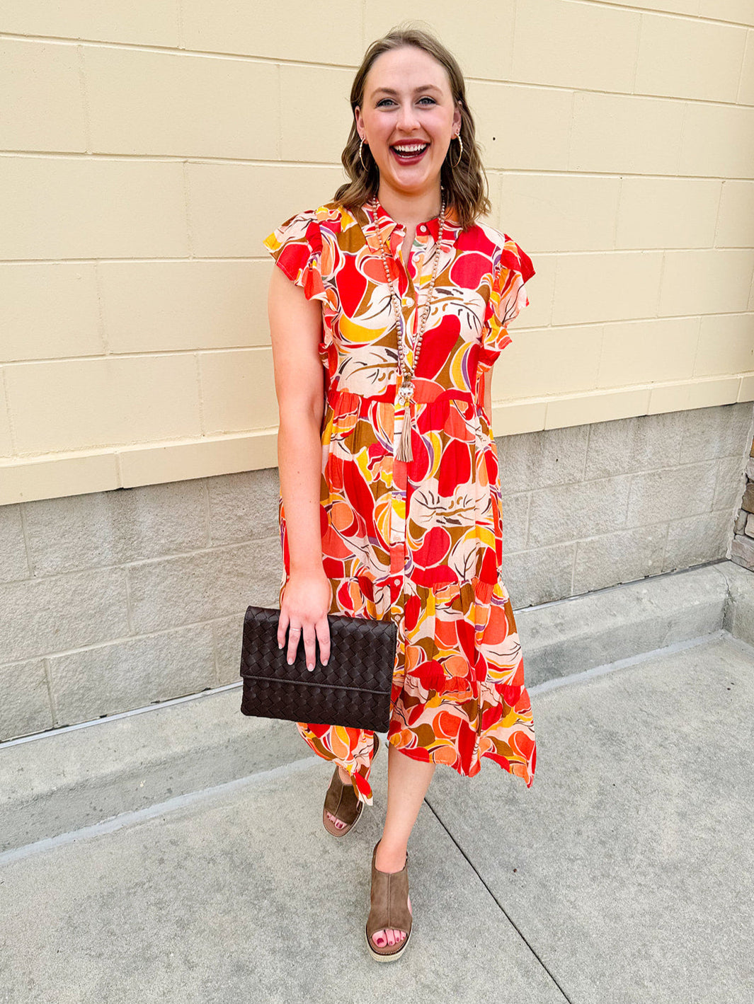 Collared midi dress with red, cream, and green pattern, ruffle sleeves, and buttons down front