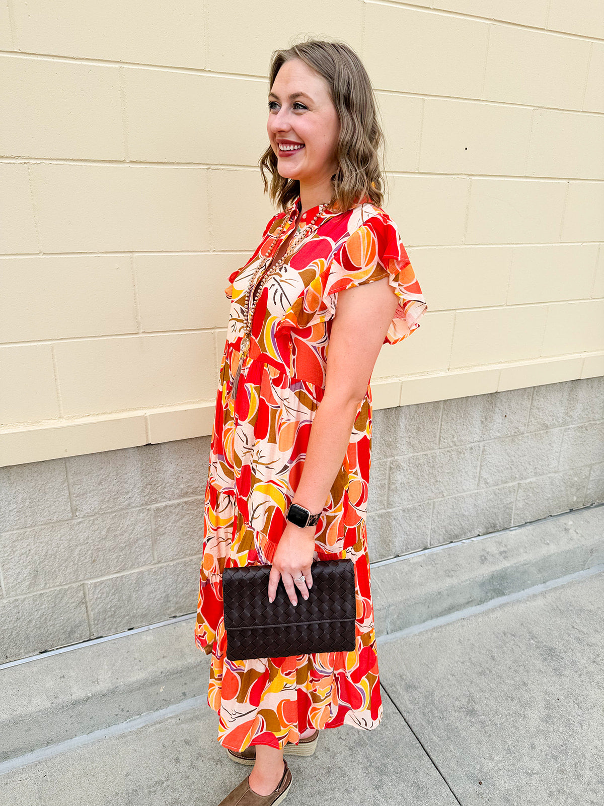 Collared midi dress with red, cream, and green pattern, ruffle sleeves, and buttons down front
