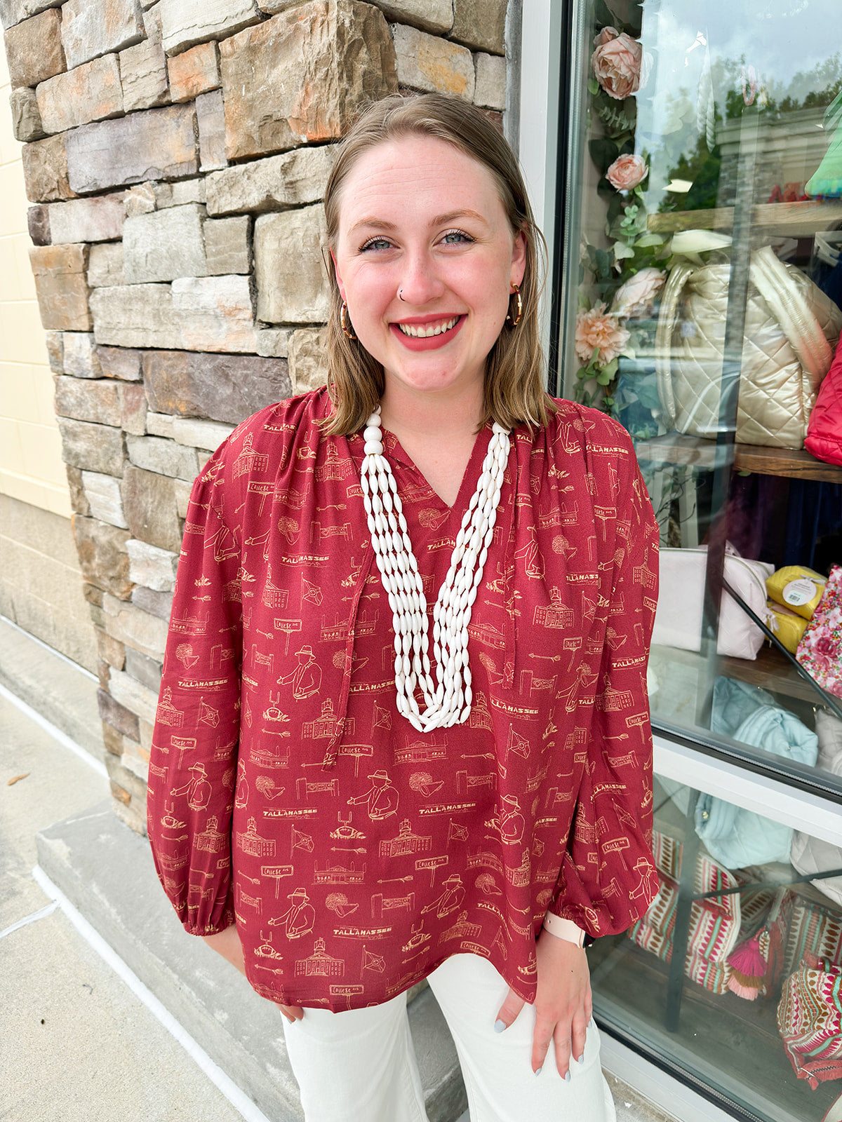 Garnet long sleeve top with v-neck, tie detail, and gold hand-drawn Tallahassee and FSU-inspired illustrations