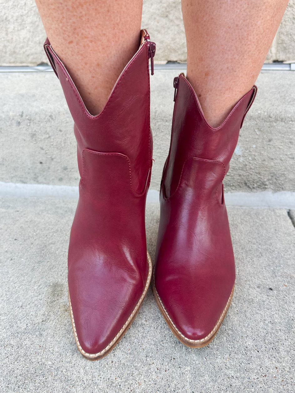Garnet-hued western ankle boots with a pointed toe, stacked leather heel, and pull-on tabs.