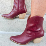 Garnet-hued western ankle boots with a pointed toe, stacked leather heel, and pull-on tabs.