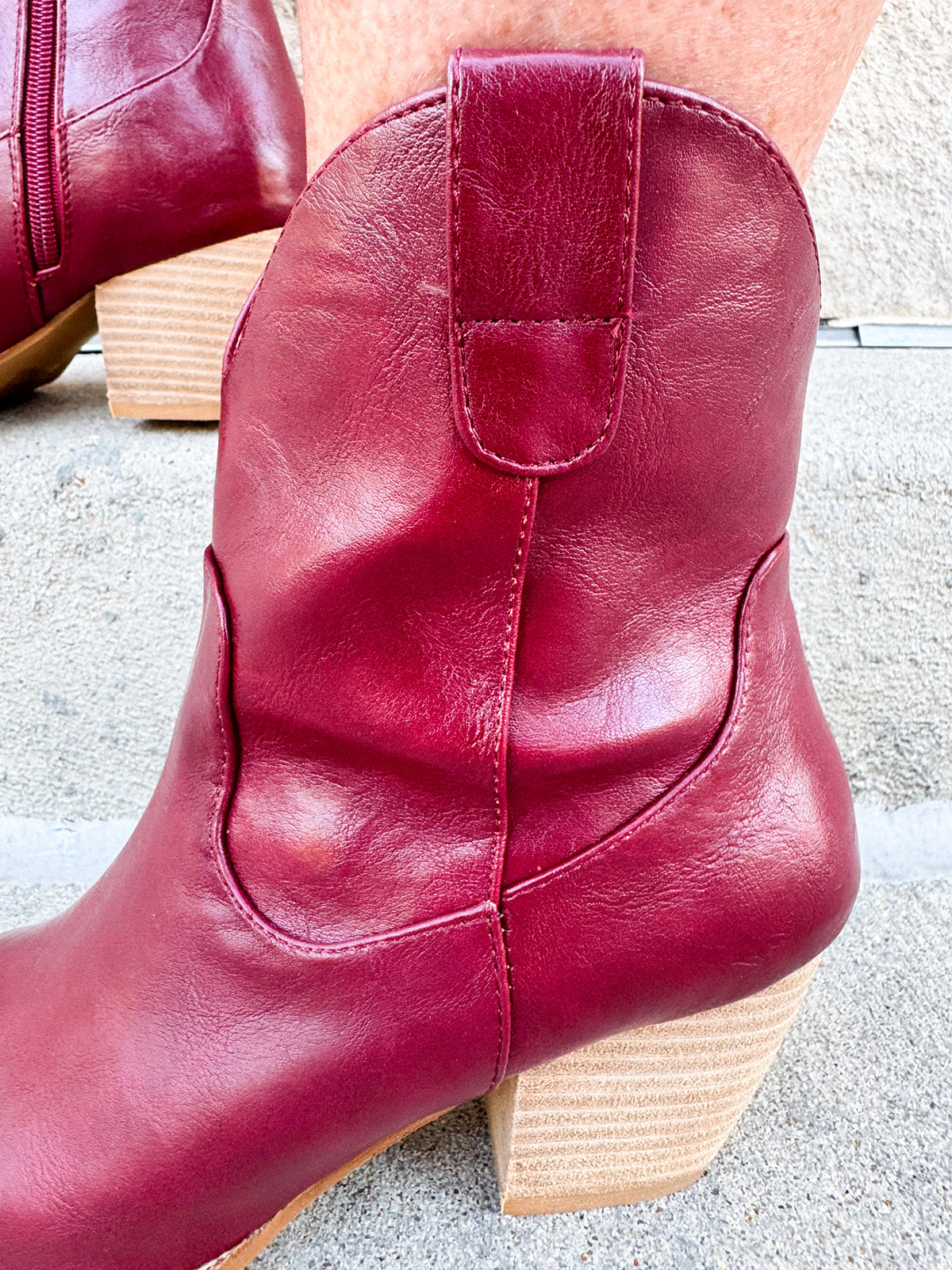 Garnet-hued western ankle boots with a pointed toe, stacked leather heel, and pull-on tabs.