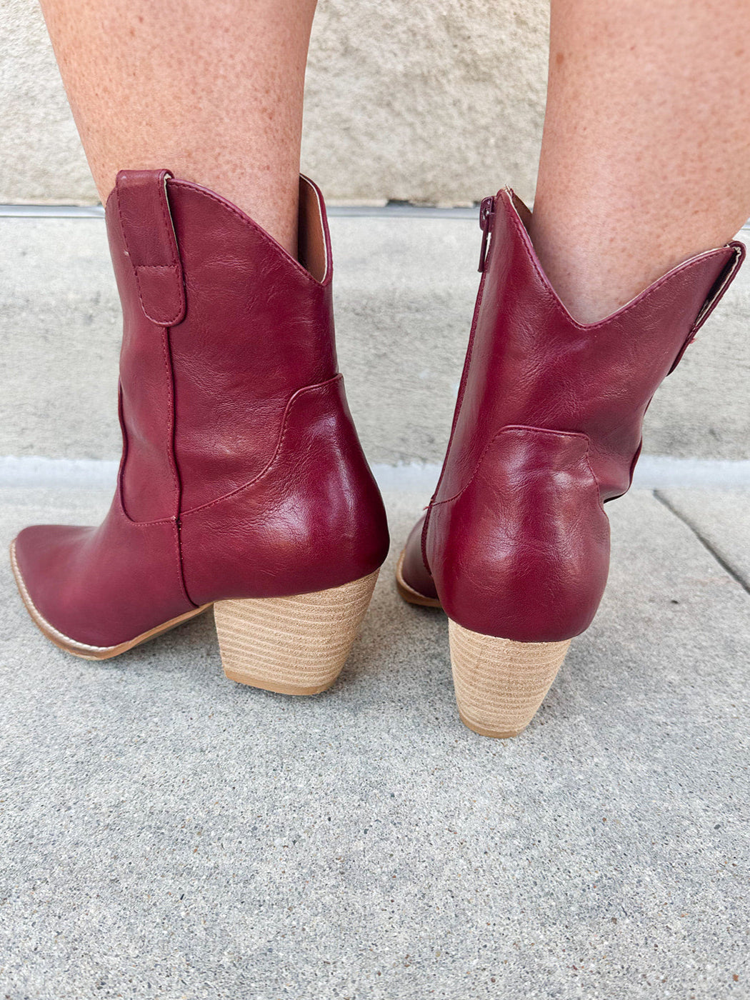 Garnet-hued western ankle boots with a pointed toe, stacked leather heel, and pull-on tabs.