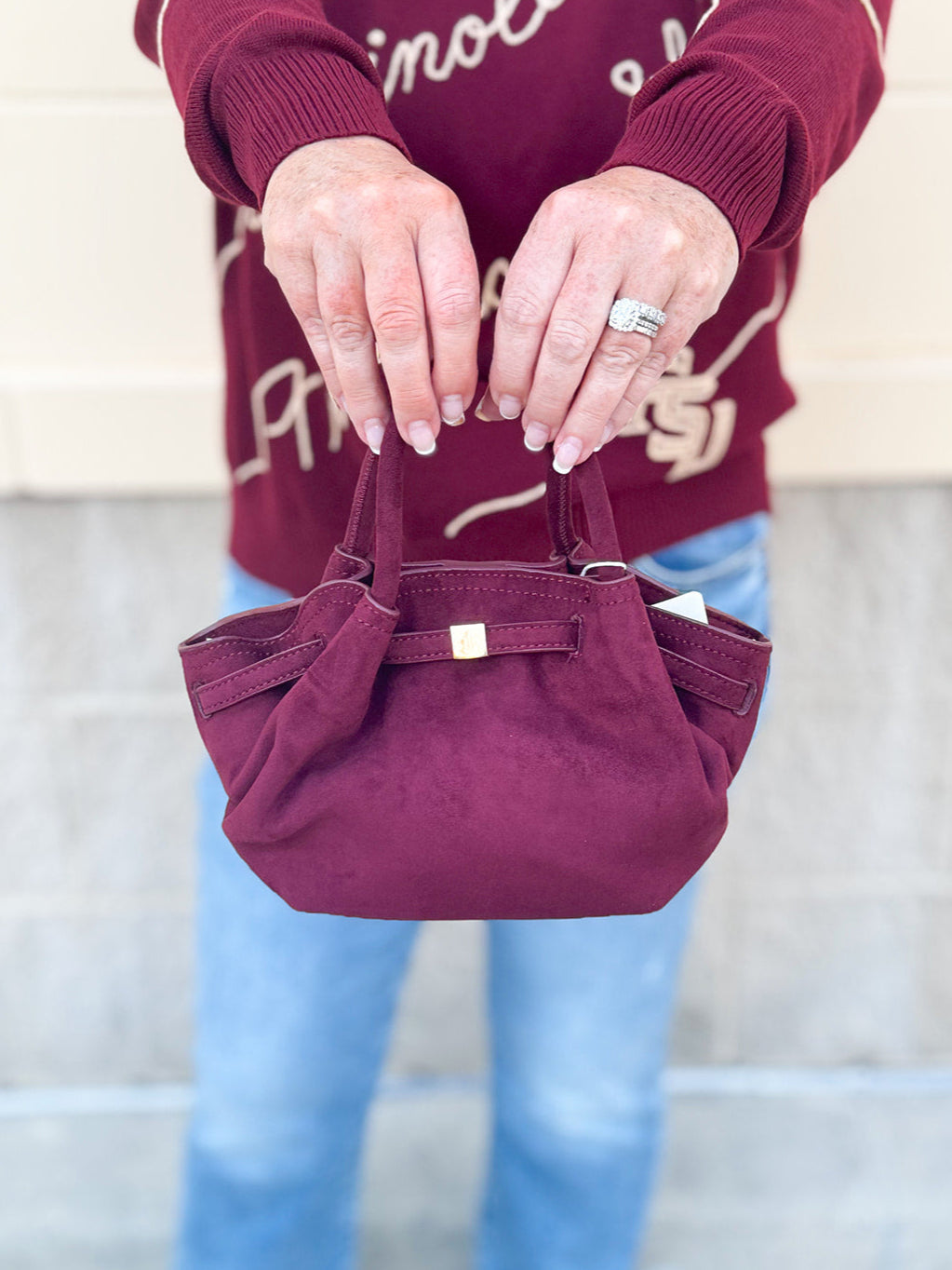 Modern structured mini tote bag with slouchy body, angular sides, top handles, and crossbody strap.