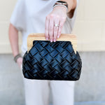 Black woven clutch with wood clasp and gold crossbody chain