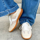 Neutral woven low-top sneakers with muted laces, round toe, and 1-inch heel, styled for casual and fashion-forward everyday looks.