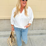 White V-neck loose-fit blouse with pleated cuffed sleeves, styled for a clean and classic outfit.