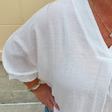 White V-neck loose-fit blouse with pleated cuffed sleeves, styled for a clean and classic outfit.
