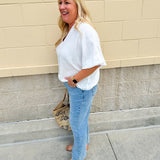 White V-neck loose-fit blouse with pleated cuffed sleeves, styled for a clean and classic outfit.