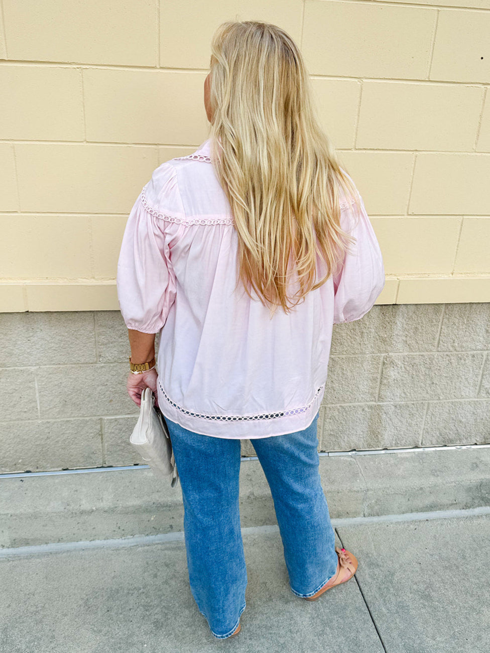 Solid pink button-down blouse with circular eyelet trim, ¾ sleeves, and pleated details, styled for a refined, feminine look.