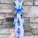 White bottle pouch with nutcracker and Christmas tree print, blue drawstring closure.