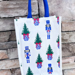 White wine caddy with nutcracker and Christmas tree print, blue handles.