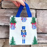 White wine caddy with nutcracker and Christmas tree print, blue handles.